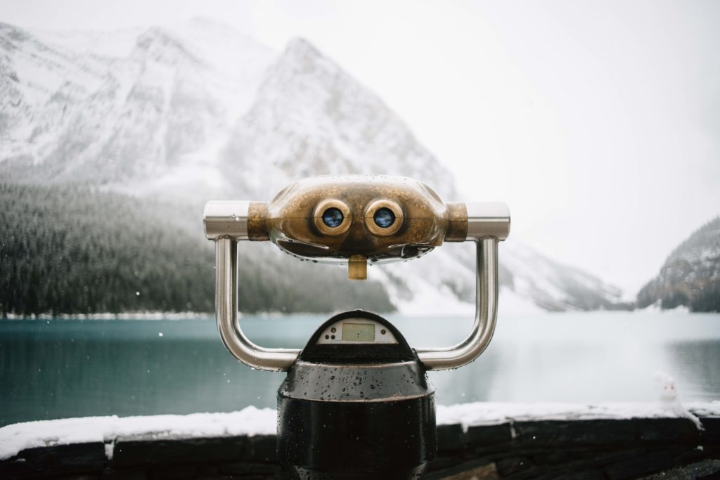 Lake and snowy mountain range in the distance with a look out pair of static binoculars 