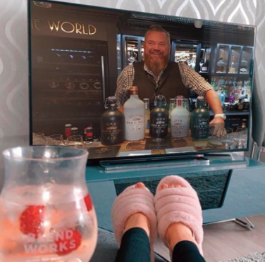 Woman with pink slippers, feet up, with a jug of cocktail, watching tv