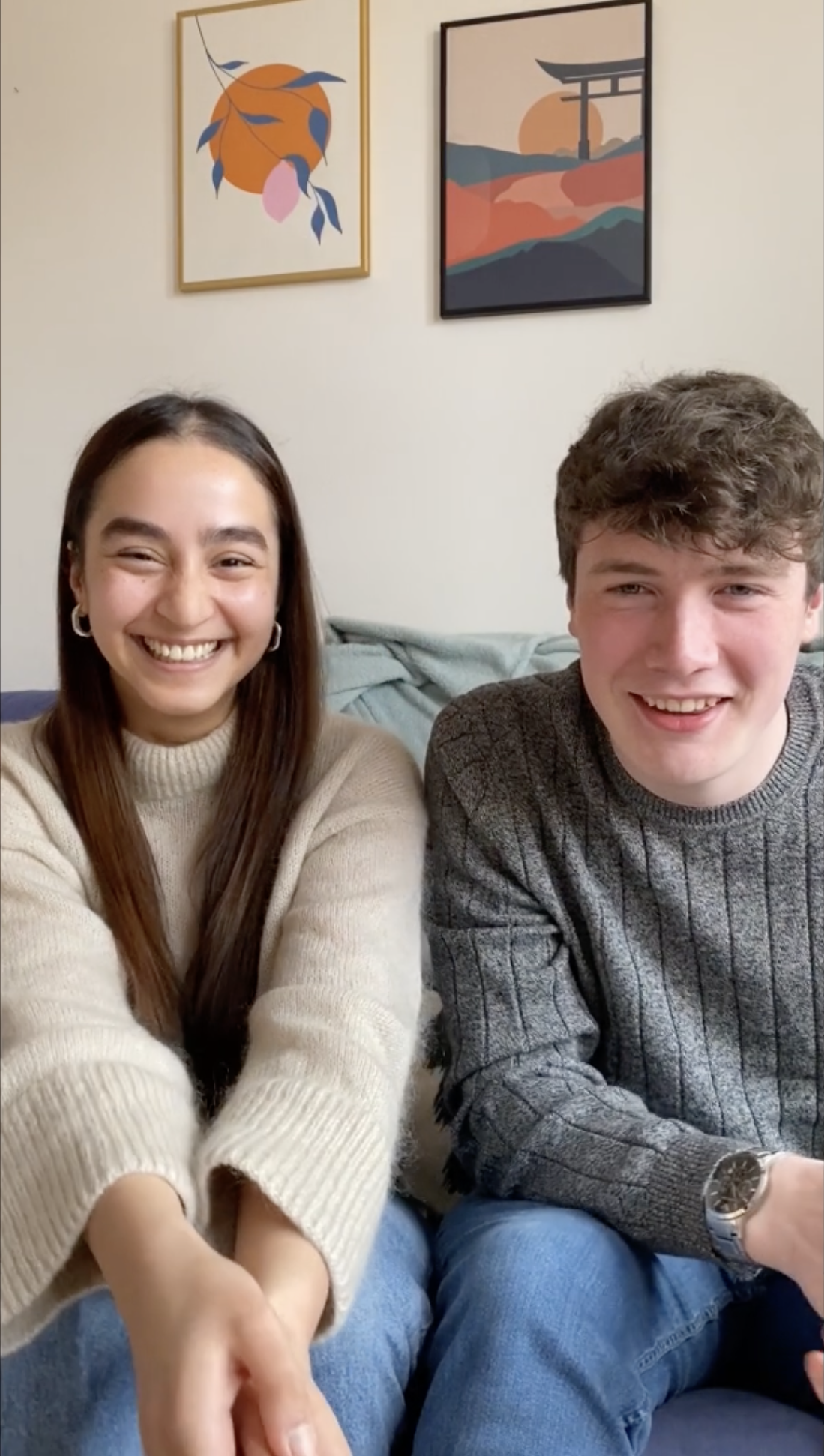 Girl and boy sitting on a sofa togther looking at the camera